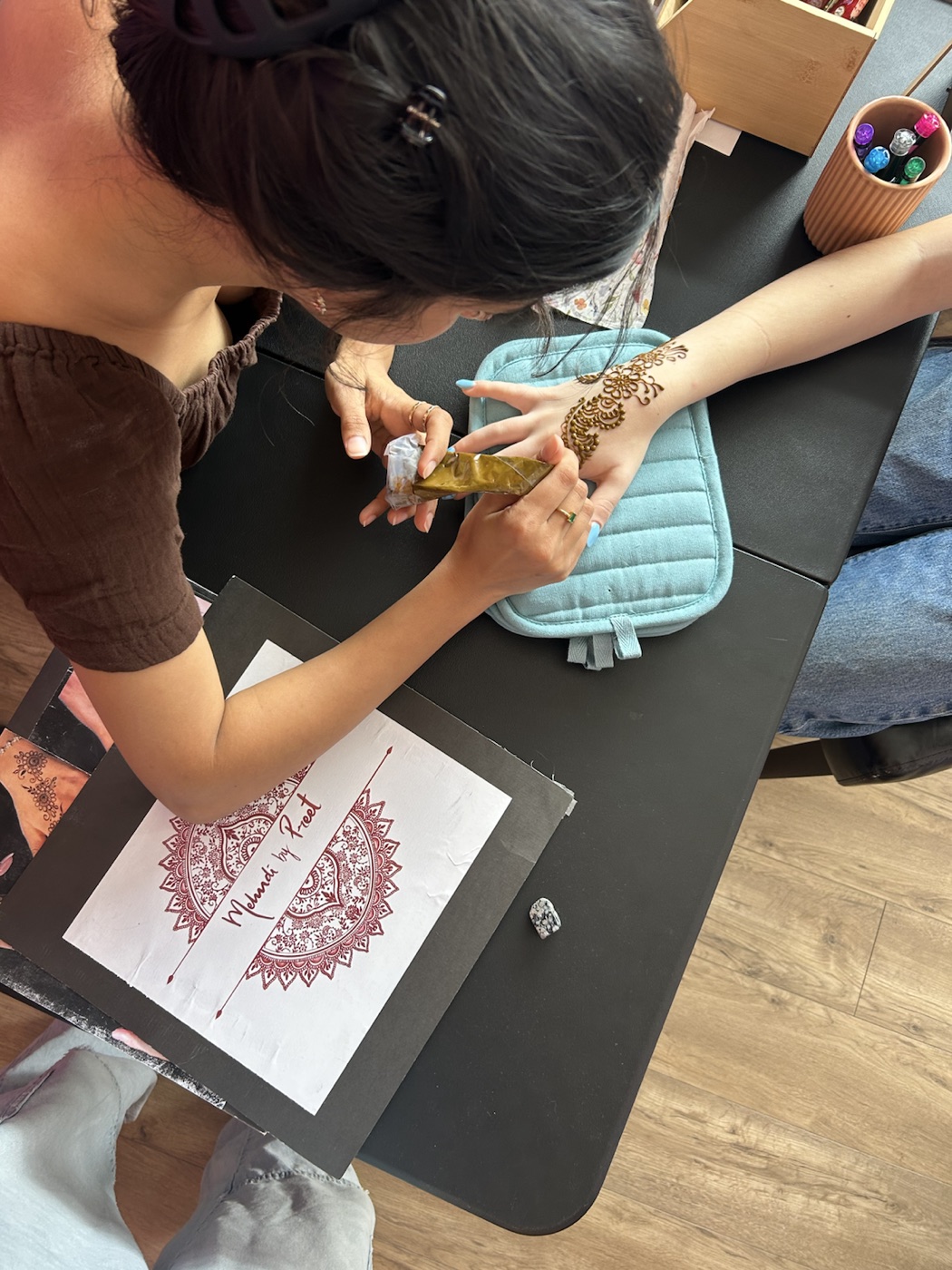Preet applying henna at a table
